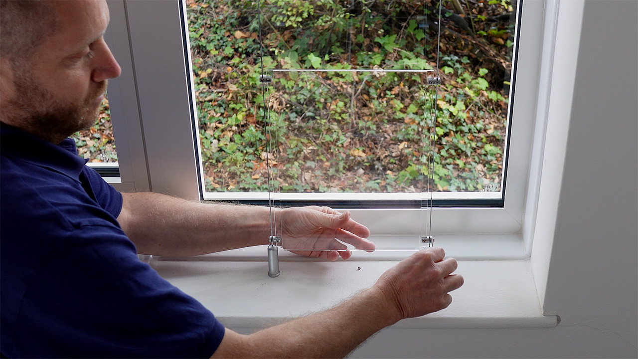 Placing an acrylic pocket between the two cables, and tightening the clamp's screws to secure the pocket in position.