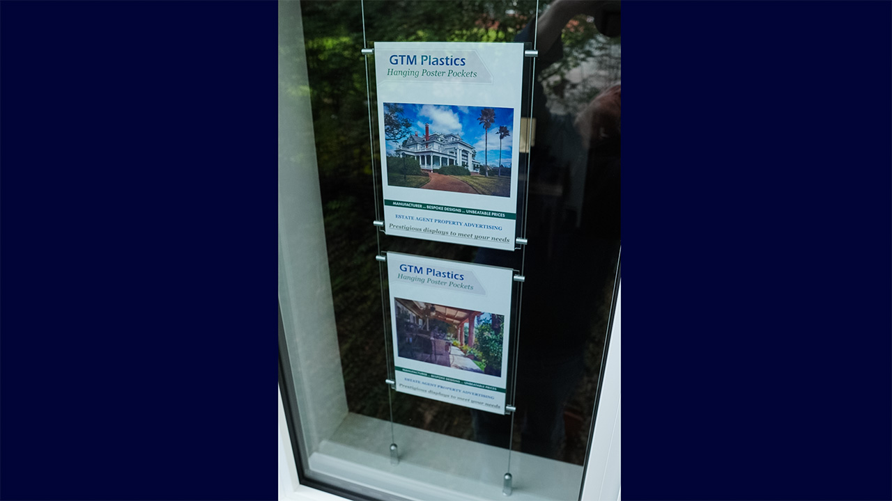 A fully assembled cable suspended poster display viewed from outside looking in through the window.