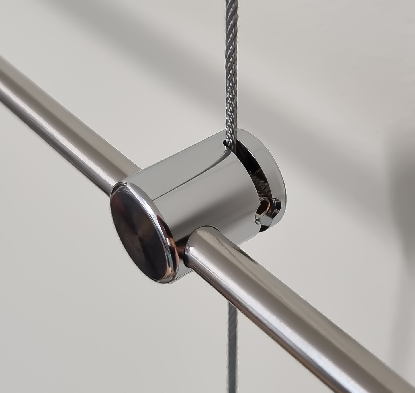 An individual chrome plated cable to rod clamp, which attaches 6mm diameter horizontal steel bar to 1.5mm diameter vertically hung cable.