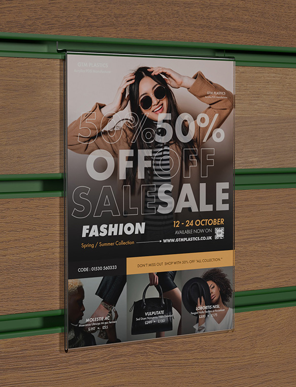 An acrylic slatwall portrait poster holder slotted into a brown wooden board which has green inserts. The poster shows people wearing various fashionable clothes for sale.