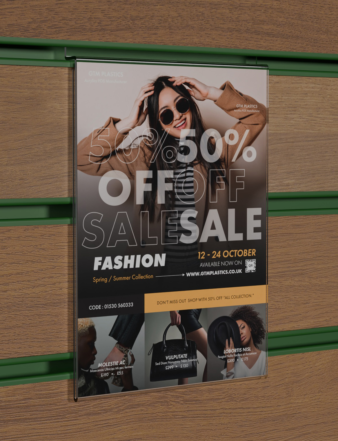 An acrylic slatwall poster holder slotted into a brown wooden board which has green inserts. The poster shows people wearing various fashionable clothes for sale.